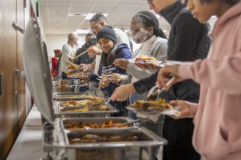 Students serve themselves food from chafing dishes.