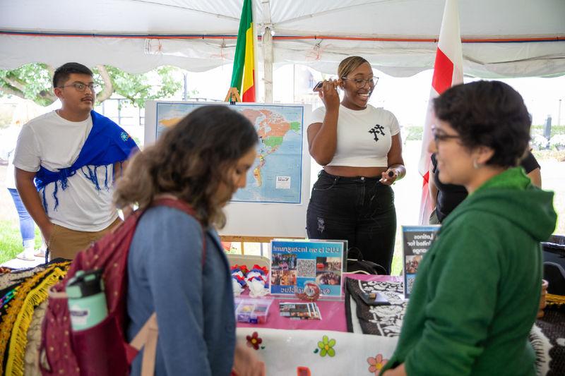 Two students learn about Latinos United for Change club while two students man the table